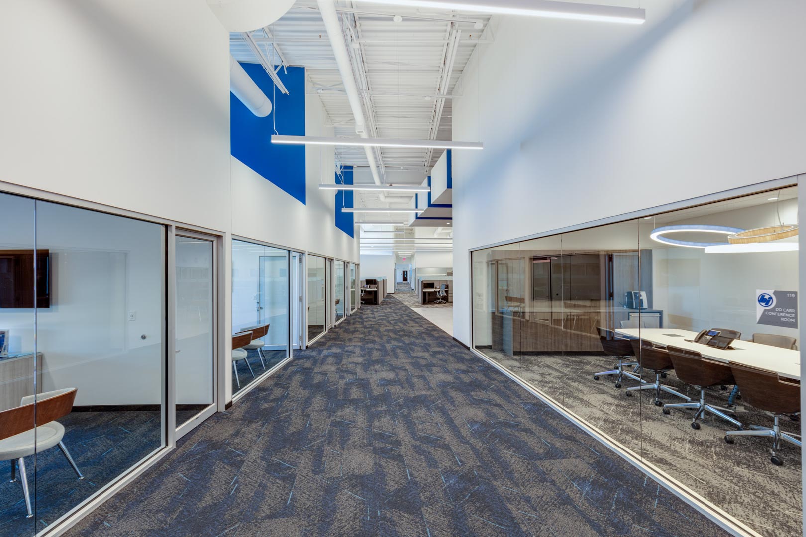 Corridor flanked by glass-walled offices and conference rooms