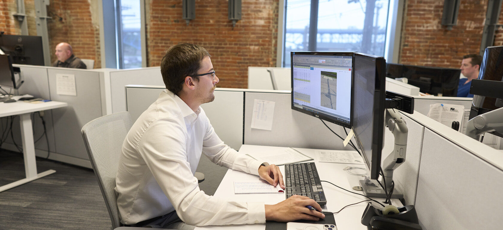 person working at computer with others working in background