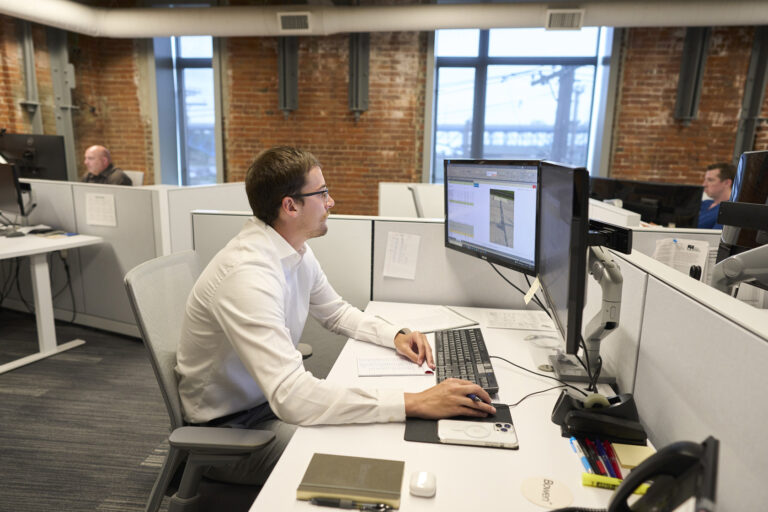 person working at computer with others working in background